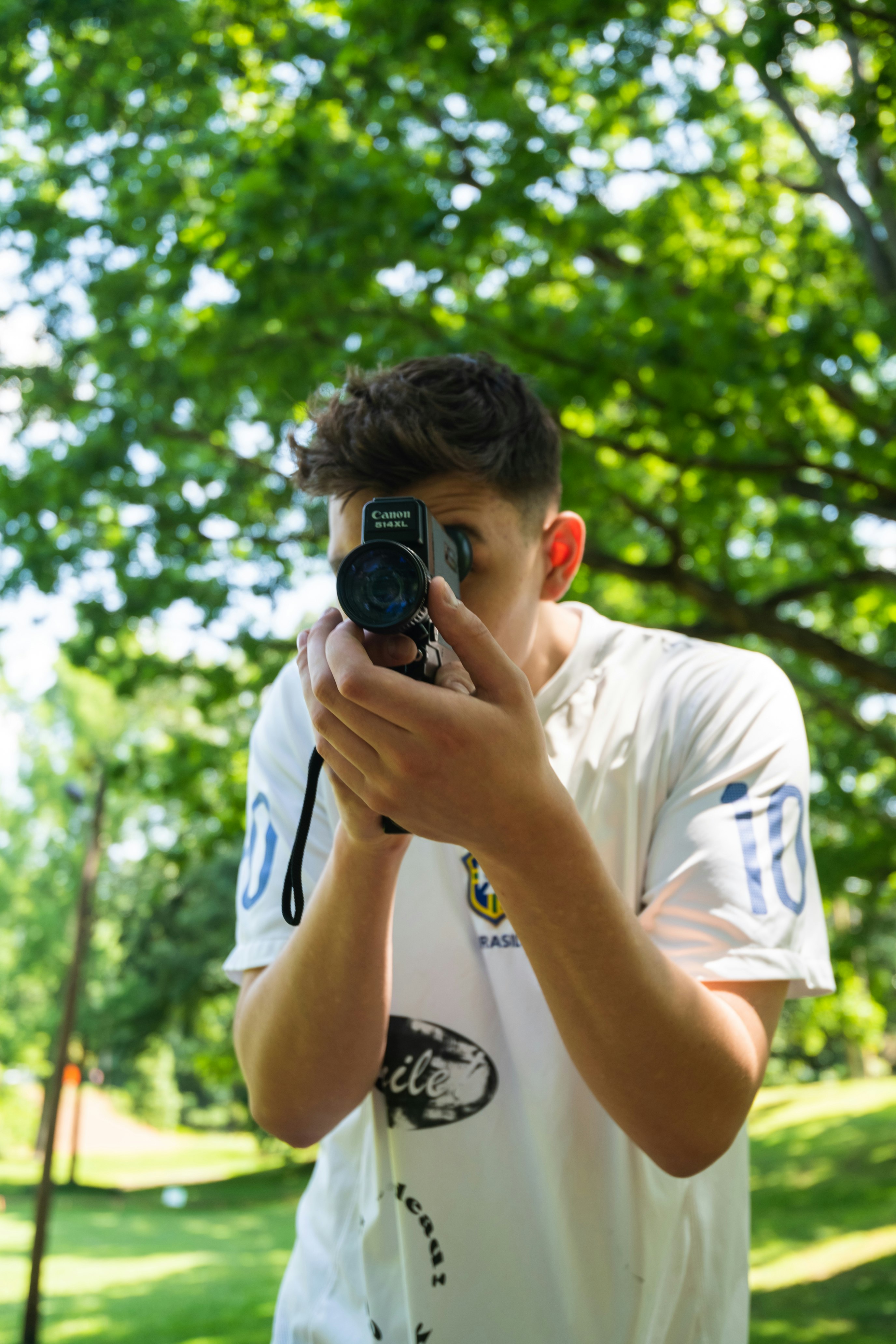 man in white crew neck t-shirt holding black dslr camera